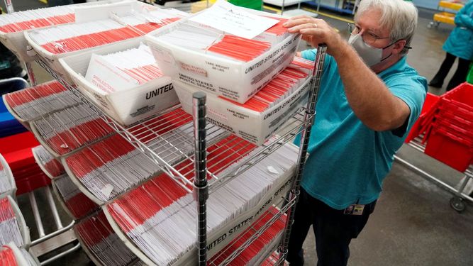 Un funcionario electoral trabaja con cajas de boletas.