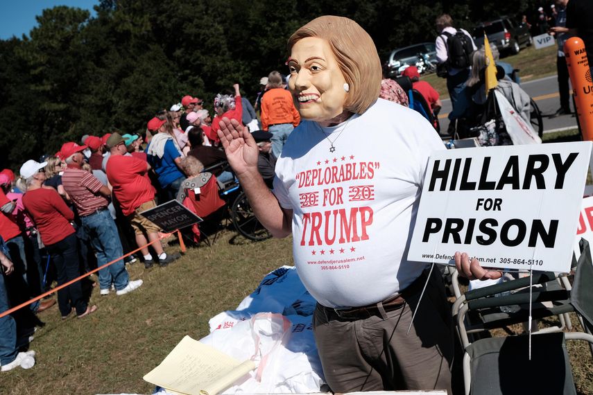 Bob Kunst lleva una máscara de Hillary Clinton mientras espera para escuchar el discurso de Trump en una campaña política en Pensacola, Florida.