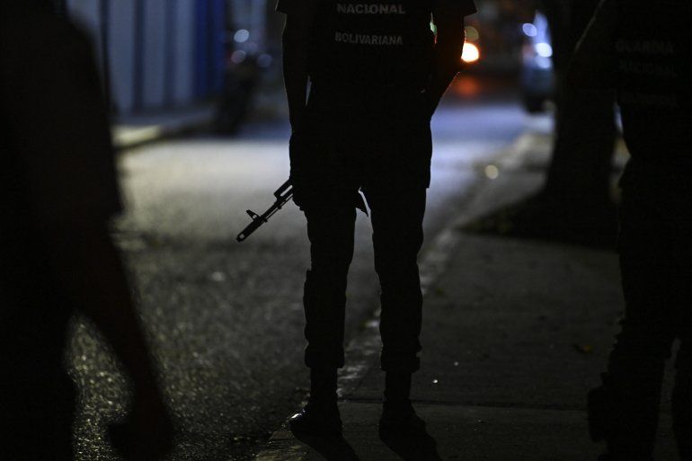 Un miembro de la Guardia Nacional Bolivariana monta guardia en la calle principal de acceso al diario venezolano El Nacional mientras miembros de un tribunal ejecutan un embargo judicial
