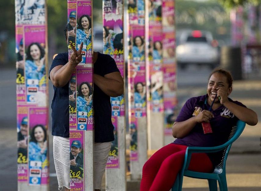 Una mujer &nbsp;detrás de &nbsp;los postes con propaganda política del oficialismo en Managua