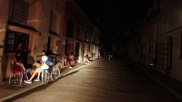 Varias personas conversan iluminadas por la luz de un automóvil en una calle del populoso barrio El Cerro, en La Habana, Cuba.