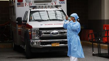 Una enfermera de urgencias se pone un protector facial despu&eacute;s de tomar un descanso junto al estacionamiento de ambulancias y otros veh&iacute;culos de emergencias m&eacute;dicas fuera del Brooklyn Hospital Center en Nueva York.&nbsp;