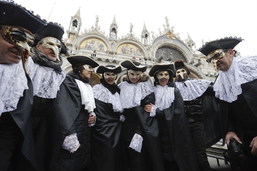 En esta foto del 11 de febrero de 2017, hombres usan mascaras, algunas de ellas de médicos de plagas, en la Plaza de San Marco en Venecia, Italia.