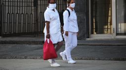 Dos enfermeras usas mascarillas faciales mientras caminan por una calle en La Habana, Cuba.