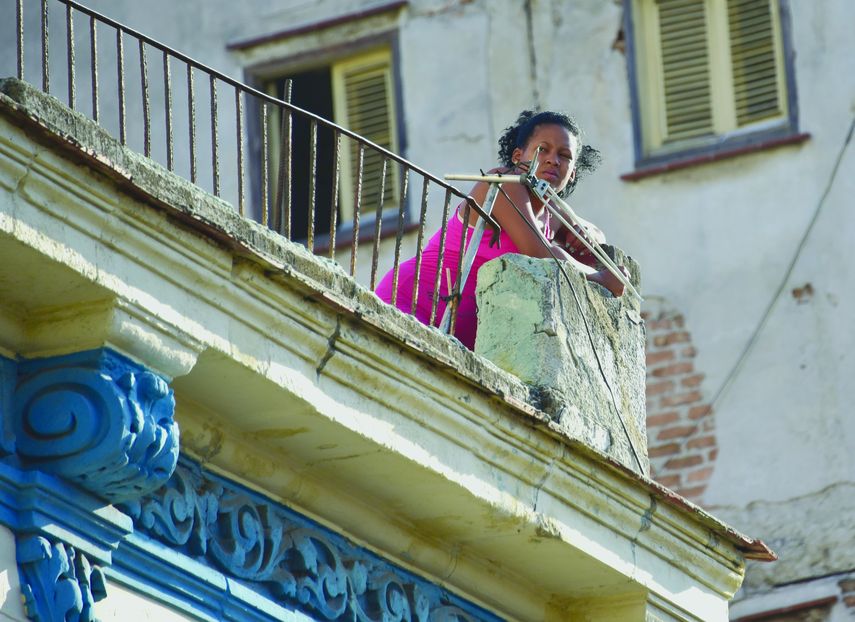Una mujer habanera mira desde un balc&oacute;n.