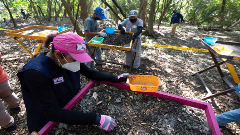 Graciela Perez, fundadora de la Red Milynali, un colectivo de familias que asisten en la búsqueda de familiares desaparecidos, examina la tierra de una fosa clandestina.