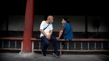 Un par de personas conversan portando cubrebocas en el Templo del Cielo, en Beijing, el sábado 18 de julio de 2020.