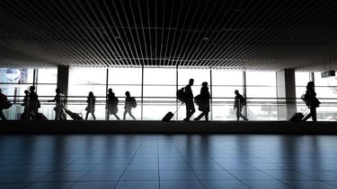 Pasajeros caminan por terminal aérea camino a la puerta de abordaje.&nbsp;