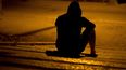 Un hombre solo sentando en medio de la noche en una acera.