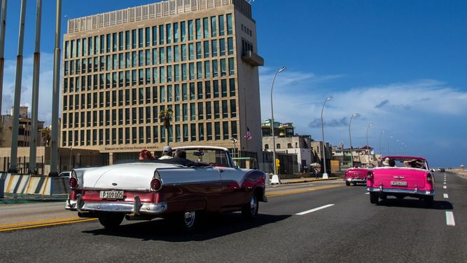 Turistas pasan por la embajada de Estados Unidos en descapotables clásicos por el Malecón, en la Habana, Cuba.