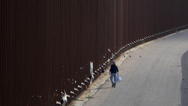 Un voluntario camina al lado del muro fronterizo en San Diego mientras entrega pañales a migrantes que esperan para solicitar asilo en Estados Unidos el jueves 11 de mayo de 2023.&nbsp;