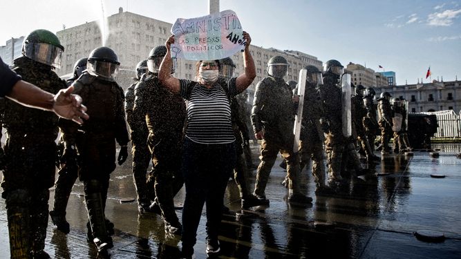Un manifestante sostiene un cartel que dice Amnistía para los presos políticos junto a la policía antidisturbios durante una protesta contra el gobierno del presidente chileno Sebastián Piñera en Santiago, el 18 de noviembre de 2020.