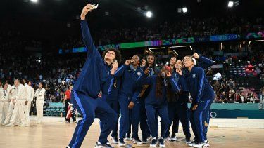 La medallista de oro Brittney Griner (izq.), número 15 de EE. UU., se toma una selfie con sus compañeras de equipo sosteniendo su medalla, después del partido por la medalla de oro de baloncesto femenino entre Francia y EE. UU. durante los Juegos Olímpicos de París 2024 en el Bercy Arena en París el 11 de agosto de 2024.