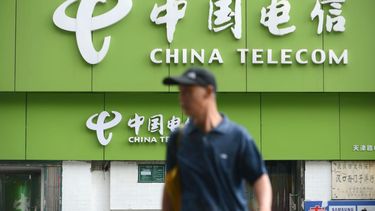 Un hombre frente a un establecimiento de la compañía China Telecom.
