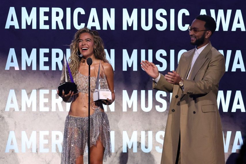 La cantante colombiana Karol G reacciona mientras el cantautor estadounidense John Legend le entrega el Premio Internacional a la Excelencia Artística y el premio al Mejor Álbum Latino por Tropicoqueta durante los American Music Awards en el MGM Grand Garden Arena de Las Vegas, Nevada, el 25 de mayo de 2026.&nbsp;