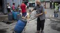 Un hombre, protegido con una mascarilla, empuja un recipiente que llenó de agua en un grifo callejero, en Caracas, Venezuela, el 20 de junio de 2020. Un hombre, protegido con una mascarilla, empuja un recipiente que llenó de agua en un grifo callejero, en Caracas, Venezuela, el 20 de junio de 2020.