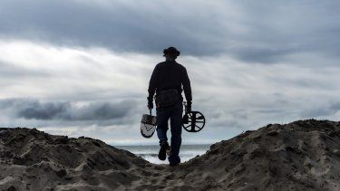 Josh Snider, que busca objetos con detector de metales, camina por una duna para buscar metales junto a una playa antes de una tormenta, el miércoles 31 de enero de 2024 en Ventura, California. 