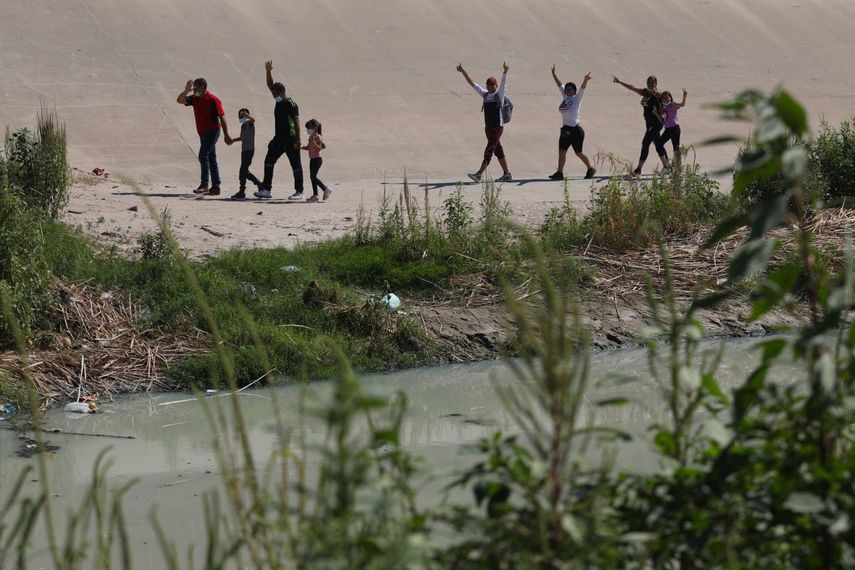 Migrantes venezolanos levantan los brazos en gesto de saludo después de cruzar el Río Bravo, o Río Grande para solicitar asilo político, visto desde Ciudad Juárez, Estado de Chihuahua, México, el 12 de septiembre de 2022.