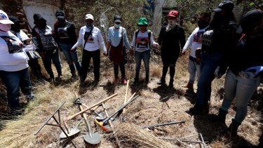 Miembros del colectivo Guerreros Buscadores se toman de la mano mientras rezan antes de trabajar en una casa abandonada durante un nuevo día de búsqueda de sus familiares desaparecidos en Guadalajara, estado de Jalisco, México, el 13 de abril de 2025.