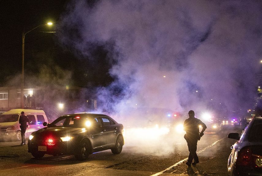 Policías de Oakland caminan entre el humo durante una protest contra la brutalidad policial en Oakland, California, la noche del viernes 16 de abril de 2021.&nbsp;