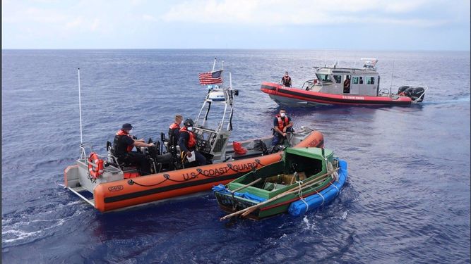 Dos embarcaciones de la Guardia Costera aparecen en la imagen junto a un bote en el que nueve cubanos intentaban llegar a las costas de EEUU. Archivo.