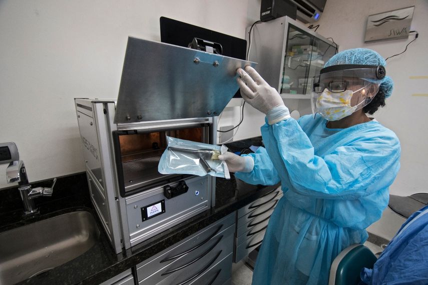 Un asistente de dentista sostiene utensilios desinfectados en la m&aacute;quina SIWA N95 desarrollada por la empresa costarricense Plasma Innova y el Instituto Tecnol&oacute;gico de Costa Rica (TEC) en San Jos&eacute;, el 22 de julio de 2020.