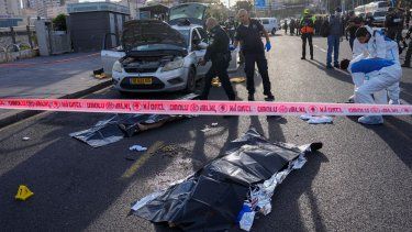 Un agente de policía israelí apunta su arma al cuerpo de un hombre implicado en un ataque en Jerusalén, el jueves 30 de noviembre de 2023. Dos hombres dispararon contra la gente en una estación de autobús en la entrada de Jerusalén, donde dejaron varios muertos y heridos.