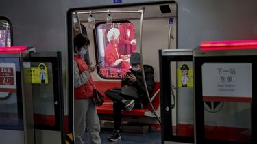 Viajeros con mascarillas leen en sus teléfonos celulares en el metro de Beijing.&nbsp; El organismo supervisor del internet en China obligará a los blogueros e influencers adquieran una licencia para poder publicar opiniones sobre ciertos temas.