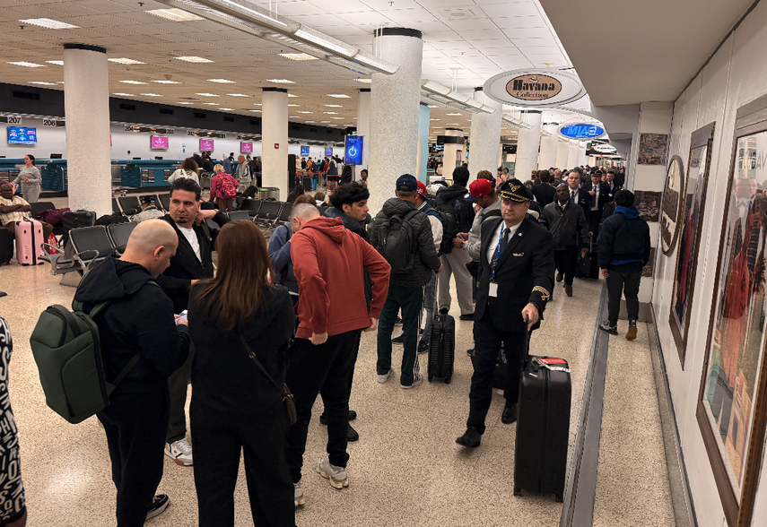 Fila de pasajeros en Aeropuerto Internacional de Miami esperando pasar el control de seguridad.