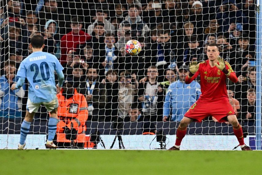 El portero ucraniano del Real Madrid #13 Andriy Lunin salva el balón disparado por el centrocampista portugués del Manchester City #20 Bernardo Silva durante la tanda de penaltis durante el partido de vuelta de cuartos de final de la Liga de Campeones de la UEFA entre el Manchester City y el Real Madrid, en el Etihad Stadium. en Manchester, noroeste de Inglaterra, el 17 de abril de 2024. &nbsp;