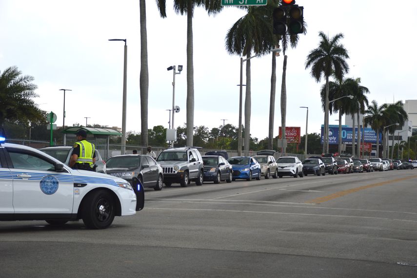 Entretanto, una larga fila de automóviles esperaba a lo largo de la calle 7 del noroeste.
