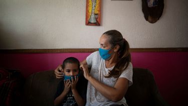En esta imagen del 24 de abril de 2020, Maylin P&eacute;rez pone una mascarilla tejida a su nieto, Daniel Cocho, en su departamento en Caracas, Venezuela.