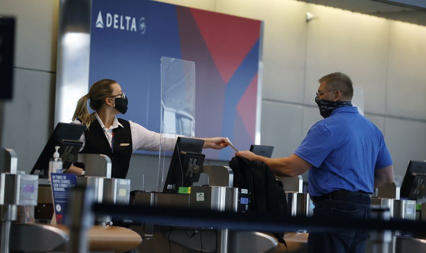 Empleada de Delta Air Lines le entrega un boleto a un pasajero.