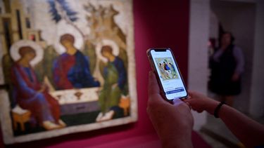 Un visitante compara el ícono de la Trinidad de Andrei Rublev que se muestra en el Museo Central Andrey Rublev de Cultura y Arte Ruso Antiguo en Moscú el 22 de mayo de 2023. Principales museos rusos ceden sus piezas a Iglesia ortodoxa.