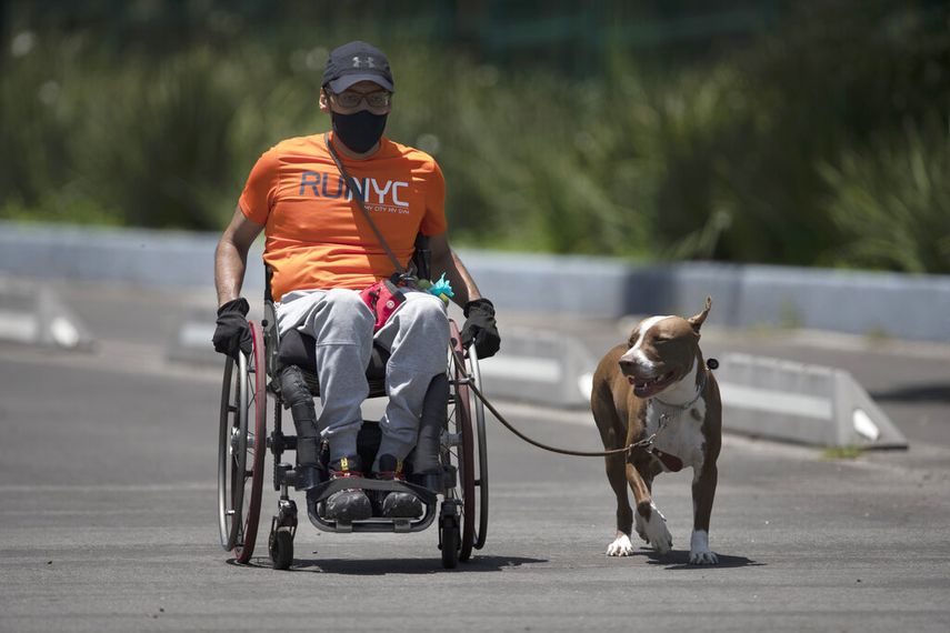 Un hombre con mascarilla para evitar contagios de coronavirus hace ejercicio en su silla de ruedas con su perro, en el parque Chapultepec de Ciudad de M&eacute;xico, el domingo 19 de julio de 2020.&nbsp;