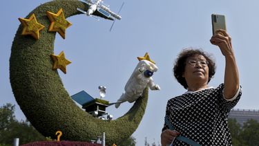 Una mujer se toma una selfie con un arreglo floral sobre los programas espaciales chinos, con motivo del Día Nacional y del 20mo congreso del Partido Comunista, en Beijing, el 26 de septiembre de 2022. 