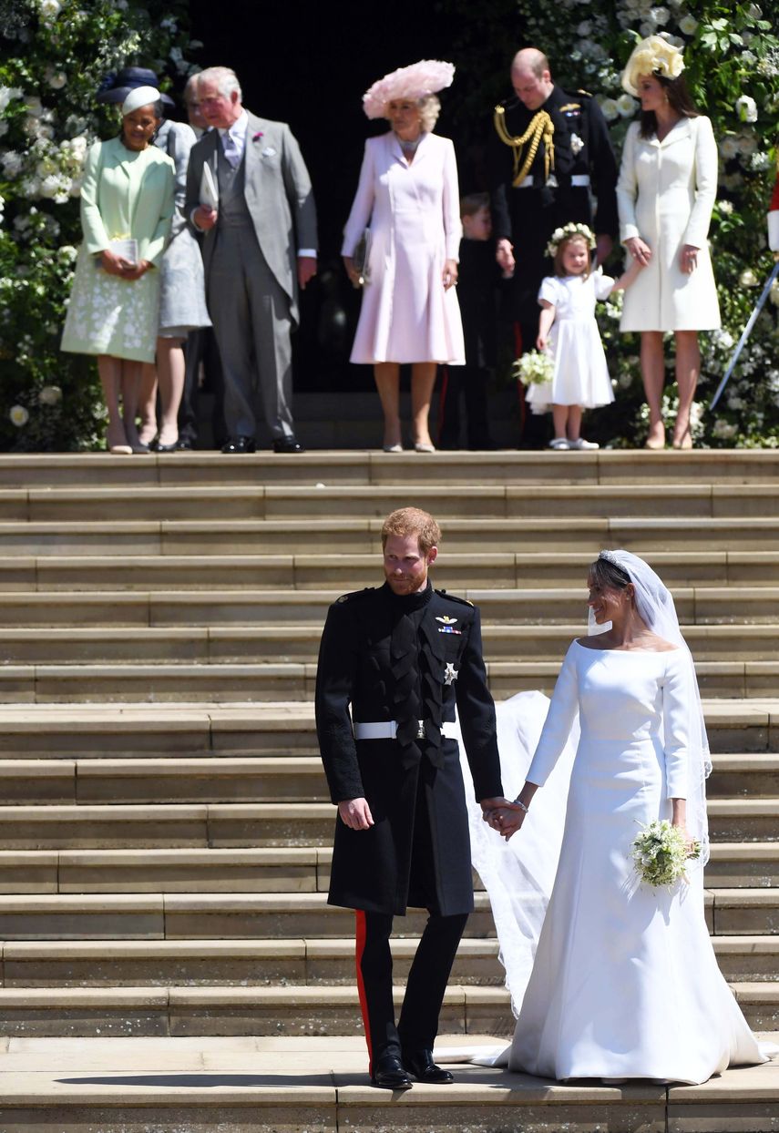 El príncipe Harry y Meghan Markle fotografiados con algunos miembros de la familia detrás:&nbsp;Doria Ragland, madre de la ahora duquesa de Sussex; el príncipe Carlos y Camila, duquesa de Cornwall; y los duques de Cambridge, el príncipe William y Kate Middleton, junto a la pequeña princesa Charlotte.&nbsp;