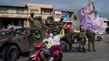Soldados hacen guardia subidos en un vehículo militar al paso de simpatizantes del candidato presidencial Daniel Noboa, de la alianza política Acción Democrática Nacional.