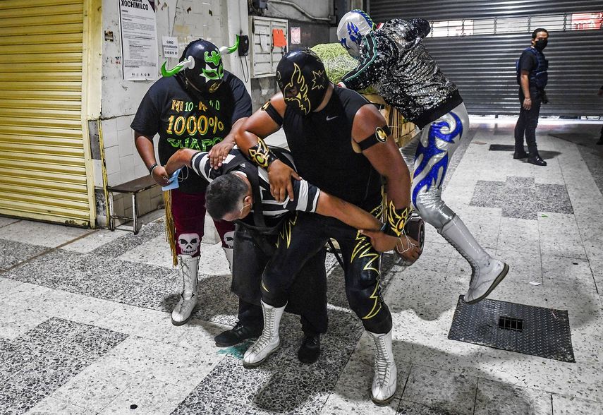 Luchadores mexicanos pretenden castigar a un hombre que no usa mascarilla mientras hacen campaña para promover su uso, en un mercado en Xochimilco, Ciudad de México, el 28 de agosto de 2020, en medio de la nueva pandemia de coronavirus.    