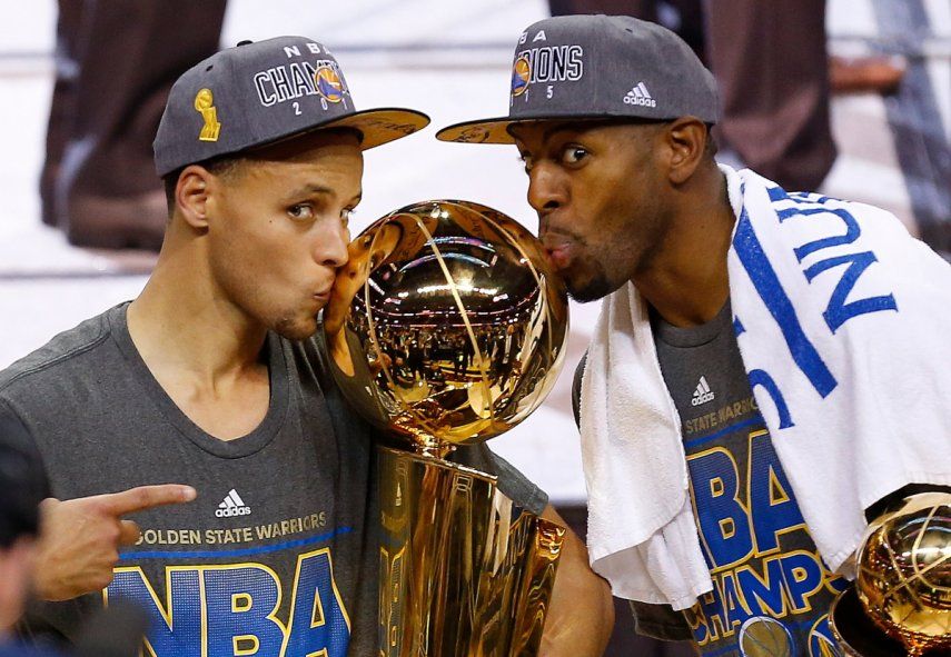 Stephen Curry, izquierda, y Andre Iguodala, de los Warriors de Golden State, besan el trofeo Larry OBrien después de derrotar a los Cavaliers de Cleveland 105-97 en el Juego 6 de las Finales de la NBA en Cleveland, el 17 de junio de 2015.&nbsp;