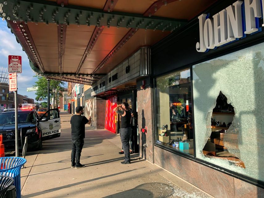 Unas personas se detienen frente a la entrada de una tienda que result&oacute; da&ntilde;ada luego de un tiroteo en Minneapolis, Minnesota, el domingo 21 de junio de 2020.&nbsp;