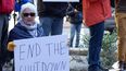 Una mujer sostiene un cartel que pide el fin del cierre parcial del Gobierno durante una protesta frente a una oficina de correos en Boston, Massachusetts.