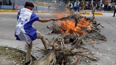 Un manifestante que usa la bandera hondureña como capa aviva el fuego durante una protesta en Tegucigalpa, Honduras, el martes 6 de agosto de 2019.