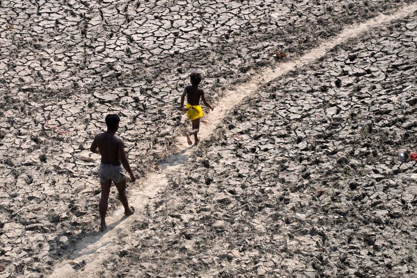 Un hombre y un niño caminan a través del lecho casi seco del río Yamuna luego de una ola de calor, el lunes 2 de mayo de 2022, en Nueva Delhi.&nbsp;