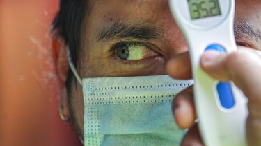 Un trabajador mide la temperatura de un hombre antes de permitirle ingresar al mercado de La Vega en medio de la pandemia del nuevo coronavirus en Santiago de Chile, el domingo 19 de julio de 2020.&nbsp;