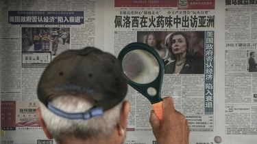 Un hombre lee la prensa con una lupa en Pekín.