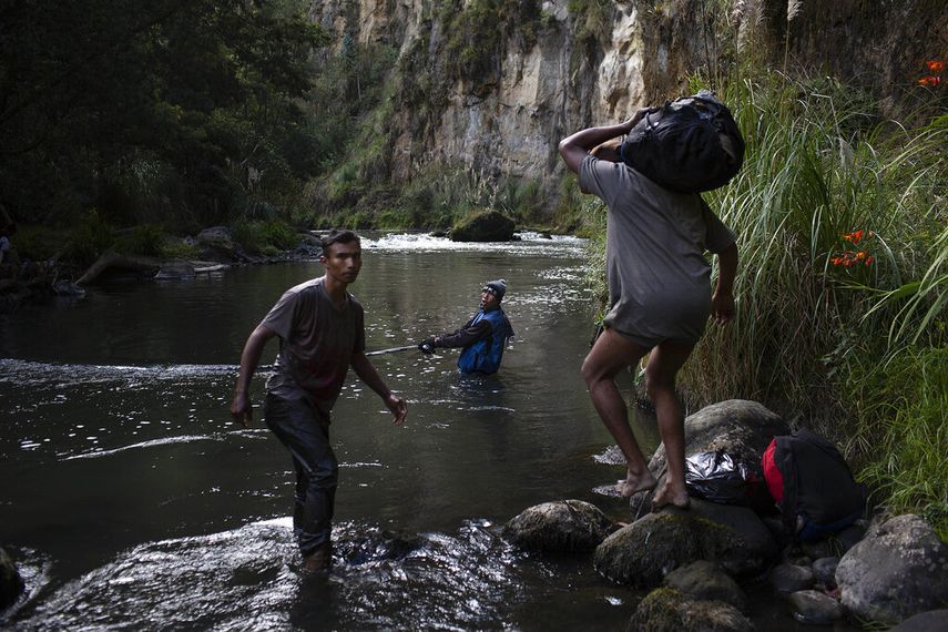 Leonel y Pedro ayudan a otro migrante venezolano en el río Guaitara a cruzar ilegalmente a Ecuador.