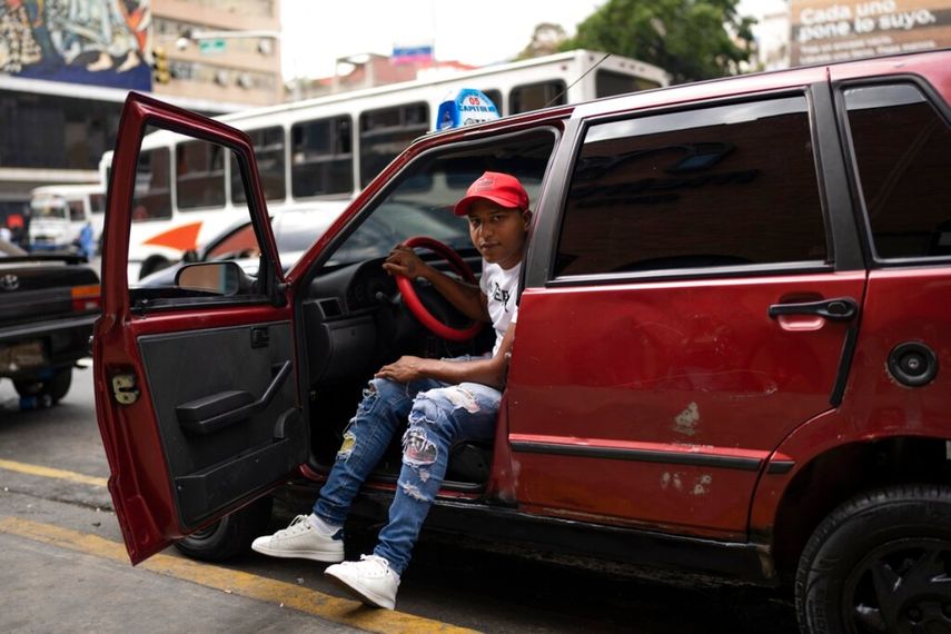 César Sandoval, conductor de taxi, posa con su auto en Caracas.