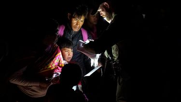 Migrantes muestran sus documentos a un agente de la Patrulla Fronteriza mientras son procesados después de cruzar la frontera, cerca de Yuma, Arizona.