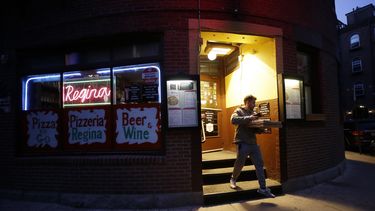 Un cliente sale de una pizzer&iacute;a en el barrio de North End, en Boston, el lunes 16 de marzo de 2020.